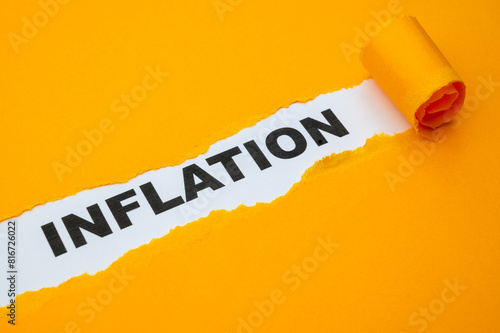 White surface, with the word Inflation in black, underneath torn and rolled yellow cardboard. 