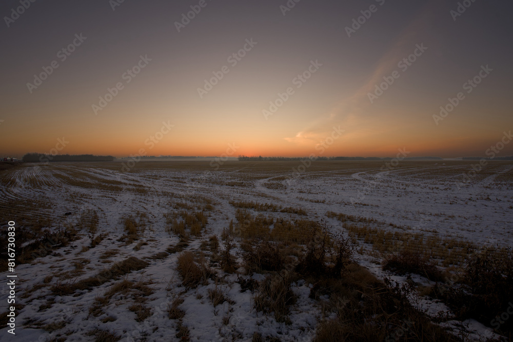 Breathtaking winter sunset with the glowing orange hue of the sun rising over a sprawling plain.