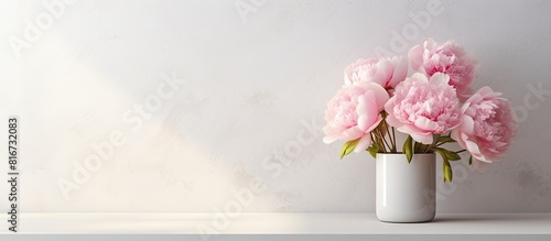 Fototapeta Naklejka Na Ścianę i Meble -  In the room against the white wall there is a vase holding a stunning bouquet of peonies There is copy space available for adding text