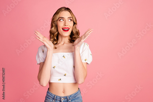 Photo portrait of pretty young girl raise hands shocked look empty space wear trendy white outfit hairdo isolated on pink color background