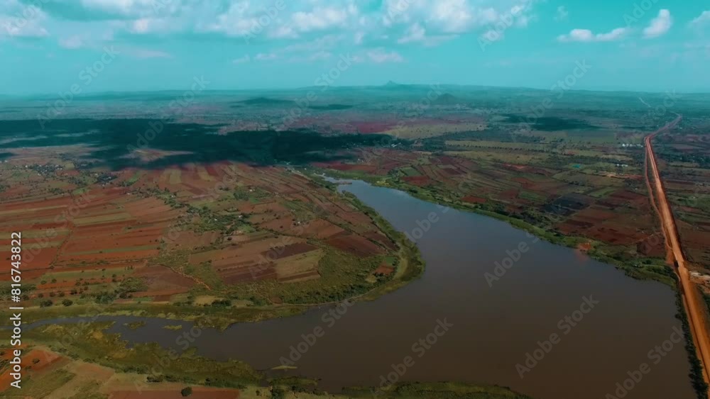 Drone shot over a small lake between colorful valleys under a blue sky Drone shot over a small lake between colorful valleys under a blue sky