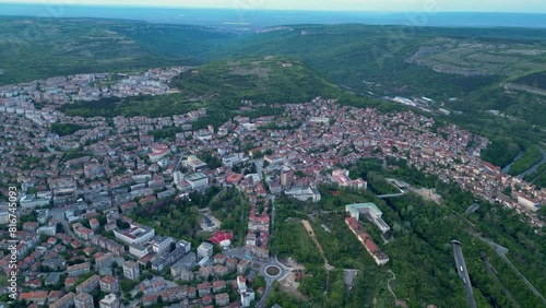 Aerial drone shot of the city of Veliko Tarnovo in Bulgaria. Yantra river,  Tsarevets, Trapezitsa, and Sveta Gora seen from above. High angle footage of residential and industrial buildings at dusk.
 photo