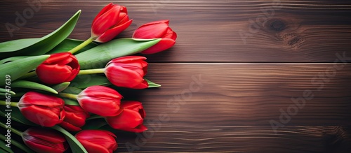 A bouquet of vibrant red tulips rests gracefully on a rustic wooden backdrop The image provides ample space for text placement