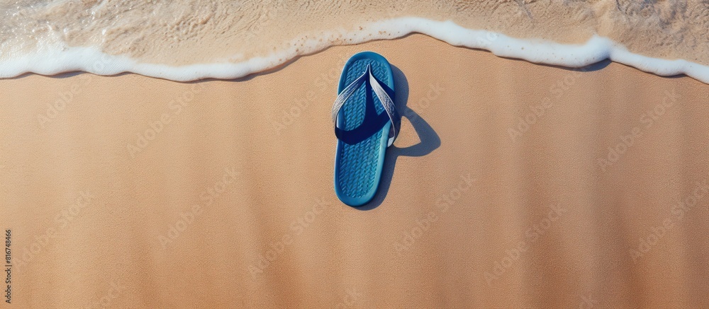Top view of a navy blue flip flop resting on a sandy beach background ...