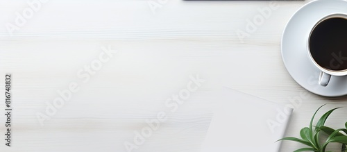 The top down view of a white office desk showcases essential elements like a laptop smartphone work supplies and a cup of coffee It offers a copy space image for text input making it an ideal designe photo