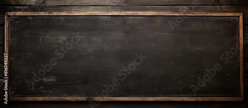 Copy space image of a black chalkboard suspended against a rustic wooden backdrop devoid of any inscription