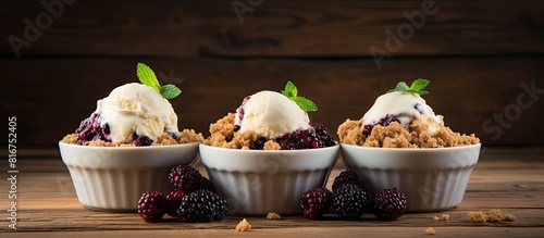 A copy space image featuring three white bowls filled with delicious blackberry crumble dessert placed on a rustic wooden background photo