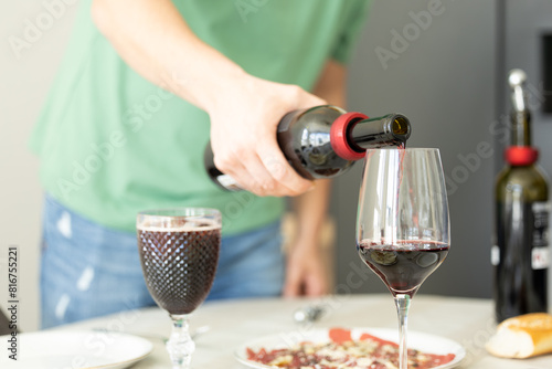 man pouring wine into glasses to toast. Man pouring red wine into wine glasses.