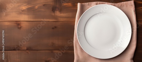 Empty plate with napkin on brown wooden table. copy space available