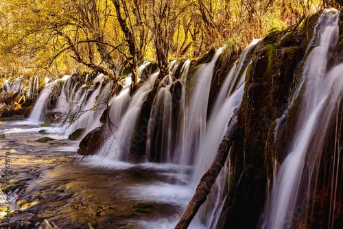 Scenic landscape of woodland featuring a cascading waterfall © Wirestock