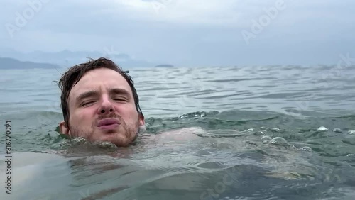 Young scared frightened man having panic attack, drown in water, phobia in the sea