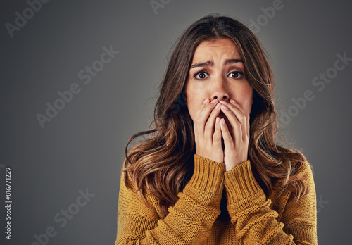 Portrait, scared and woman with fear, afraid and anxiety with secret news on grey studio background. Face, person and model with surprise, shocked and cover mouth with emotions and emoji of gossip photo
