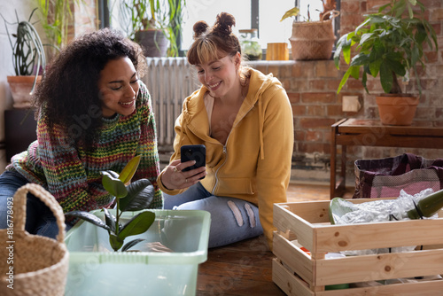 Two friends looking at smartphone sitting with moving boxes