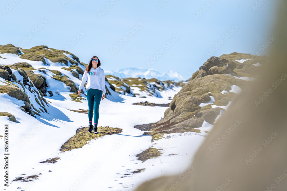 Obraz premium a young girl standing on snow covered ground and rocks and mountains