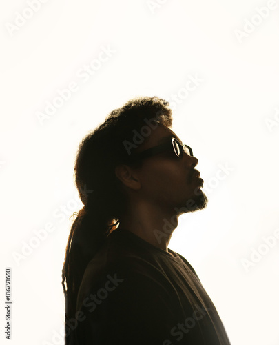 portrait of blind black man with glasses and dreadlocks. yellow white background in studio