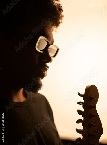 portrait of blind black man musician with glasses and dreadlocks and his guitar studio soft background