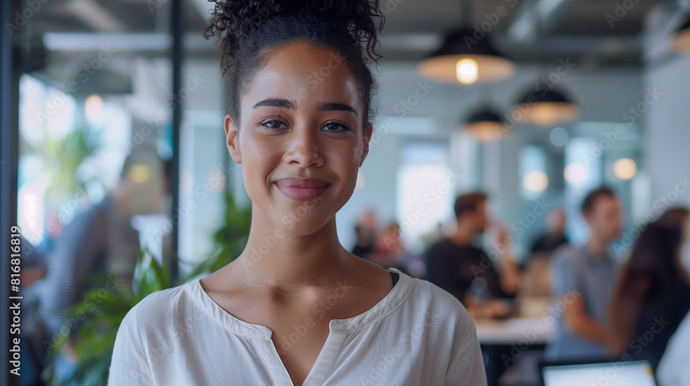 In a lively workspace, a smiling young lady is surrounded by engaged colleagues in the background In a lively workspace, a smiling young lady is surrounded by engaged colleagues in the background