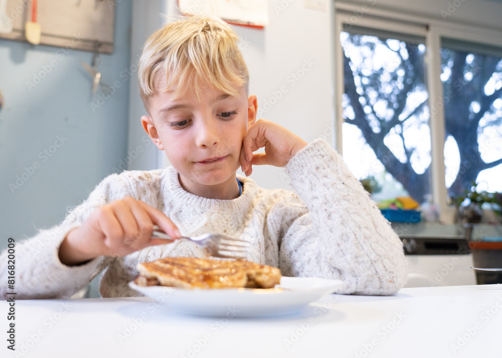 Boy having homemade pancakes for breakfast in the kitchen of his house Boy having homemade pancakes for breakfast in the kitchen of his house