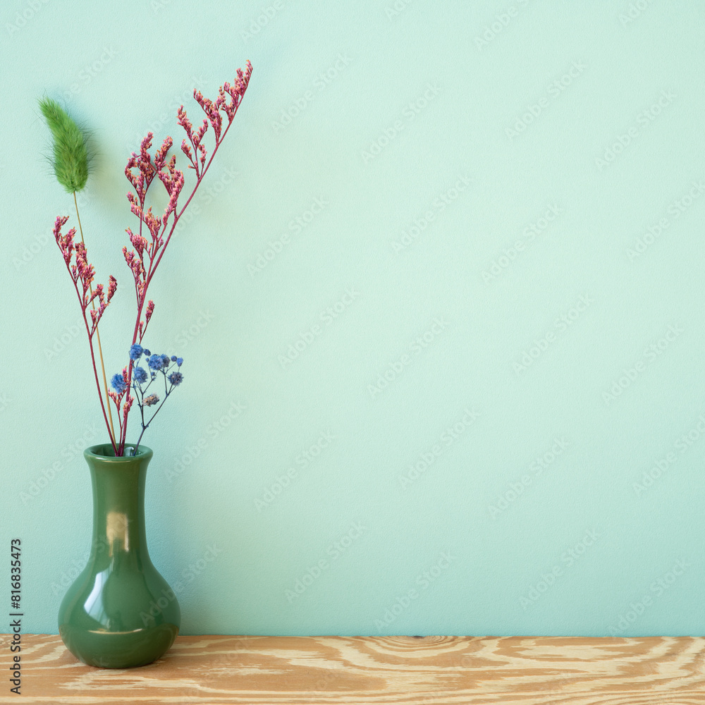 Vase of dry flower on wooden shelf. mint wall background