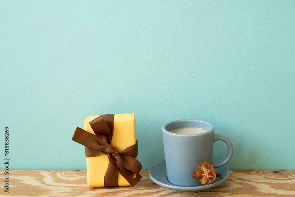 Yellow gift box and cup of latte coffee on wooden table. mint wall background