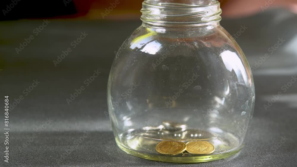 Throw coins into a glass jar. Money box. Drop money into a jar. Throw coins into a glass jar. Money box. Drop money into a jar.