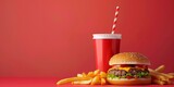 A cheeseburger, fries and a soft drink on a red background.