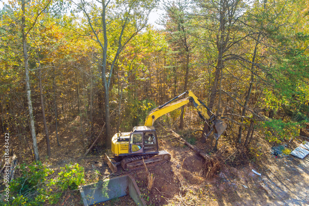 Preparation of land for construction, use of an excavator tractor to uproot trees make space for construction of house Preparation of land for construction, use of an excavator tractor to uproot trees make space for construction of house
