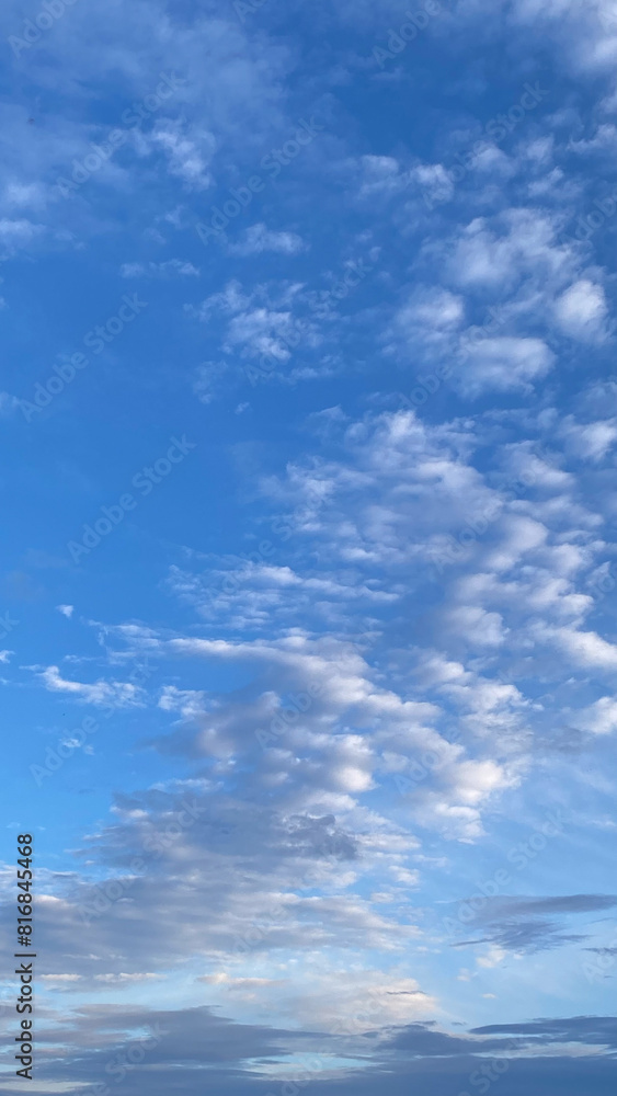 Bright blue sky filled with scattered white clouds. Perfect for a serene and calm background representing tranquility and natural beauty