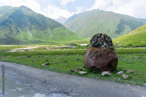 Road marker in the form of a pyramid on the edge of a gravel road among the mountains photo