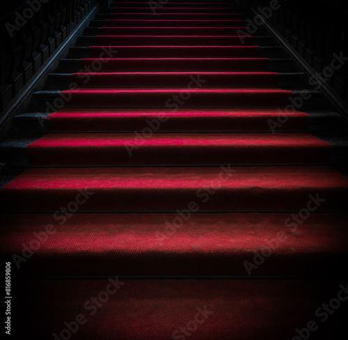 Vintage dark staircase with red carpet.