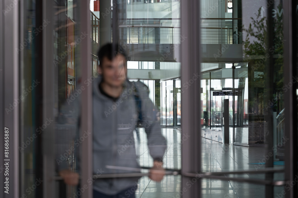 A man going out from a building, glass revolving doors