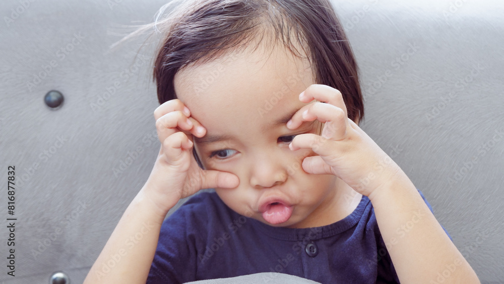 Fototapeta premium cute Asian toddler on the couch and making funny face