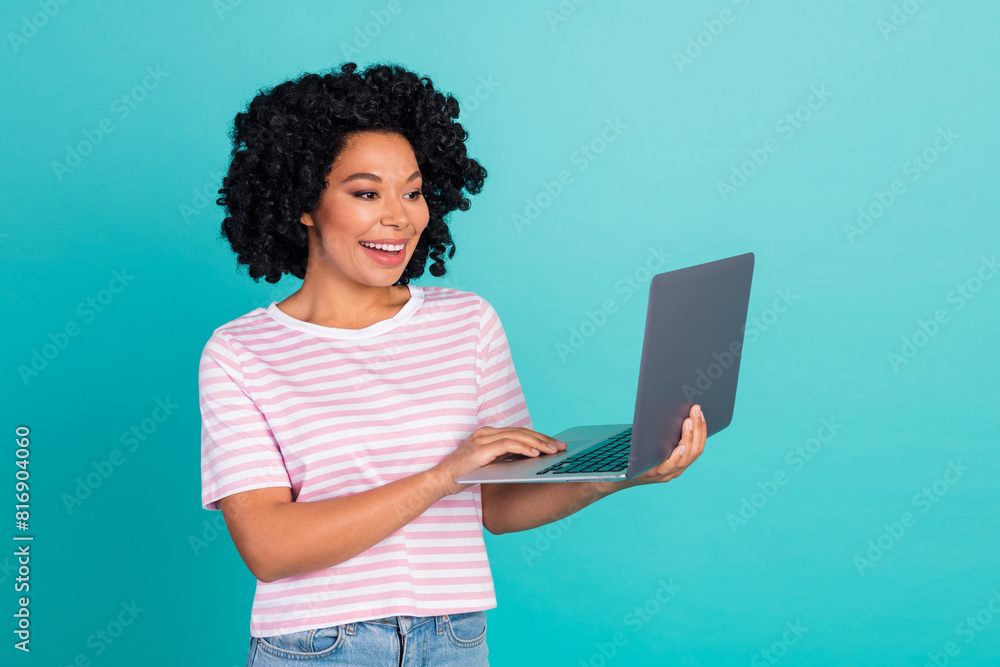 Photo portrait of lovely young lady hold netbook dressed stylish striped garment isolated on aquamarine color background Photo portrait of lovely young lady hold netbook dressed stylish striped garment isolated on aquamarine color background