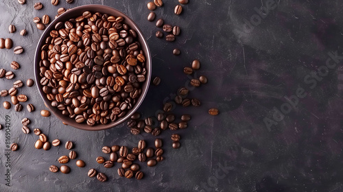 Top view of a bowl filled with roasted coffee beans on a dark textured surface, with some beans scattered around, creating a rustic and aromatic feel.