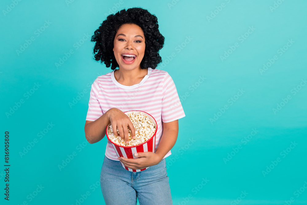 Photo portrait of lovely young lady laugh eat popcorn dressed stylish striped garment isolated on aquamarine color background Photo portrait of lovely young lady laugh eat popcorn dressed stylish striped garment isolated on aquamarine color background