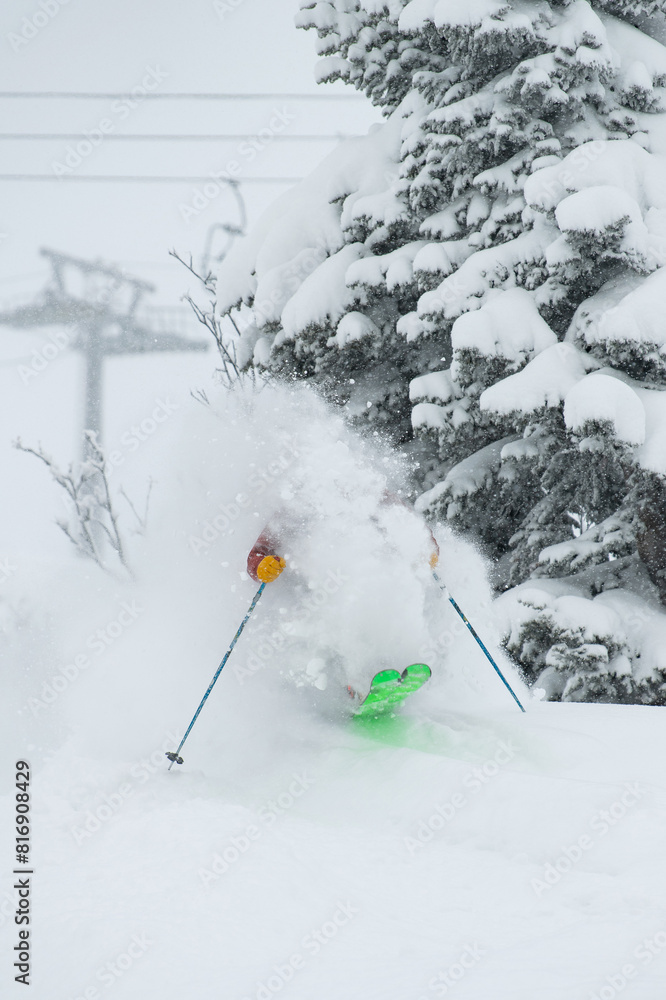 A skier in the forest in Siberia jumps out on bright skis from behind a tree in a cloud of raised snow with a chairlift in the background A skier in the forest in Siberia jumps out on bright skis from behind a tree in a cloud of raised snow with a chairlift in the background