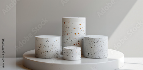 four white terrazzo cylinder podiums in different sizes, on grey background, minimalism