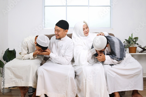 Asian Moslem children beg for forgiveness to their parents during Eid Mubarak moment photo