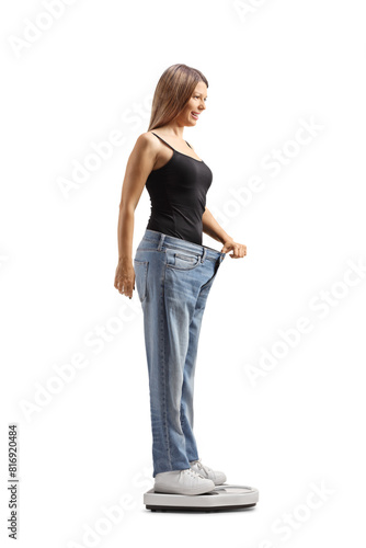 Obraz na plátně Woman wearing a big size jeans and weighing on a medical scale