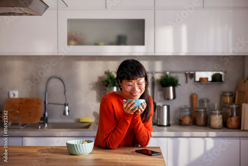 Woman relaxing at home drinking coffee at kitchen counter