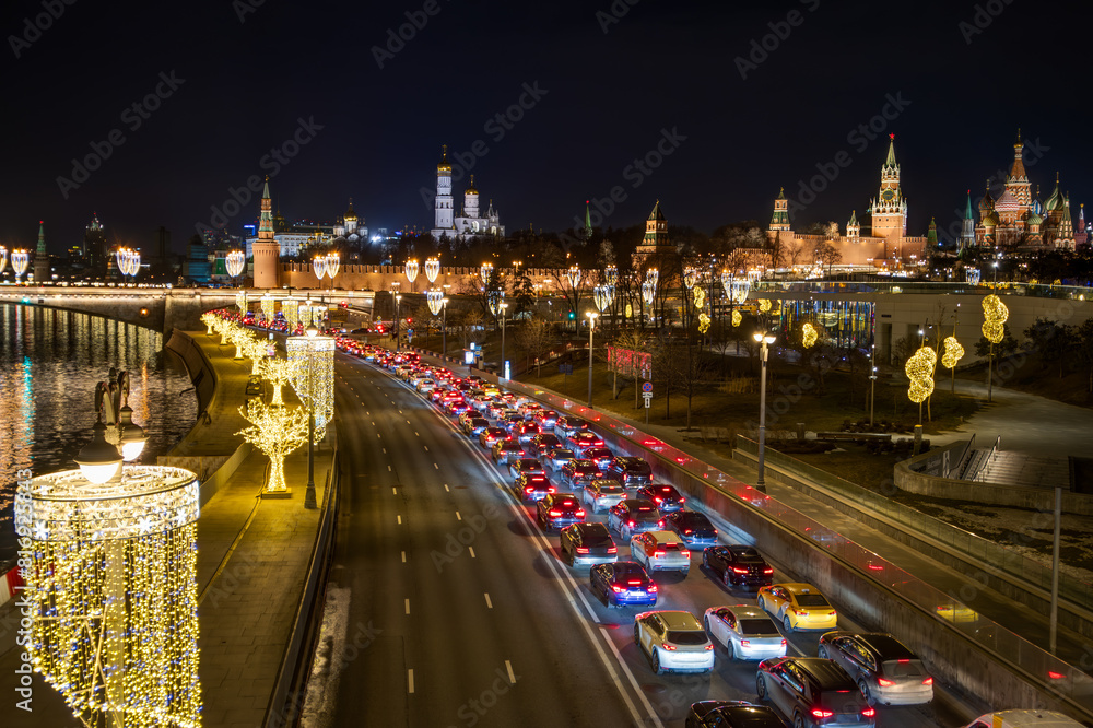 Obraz premium Moscow, Russia. Top view of Moskvoretskaya embankment. There is a traffic jam on the roadway. Many cars in a traffic jam. The Moscow Kremlin is in the distance. Beautiful street lighting.