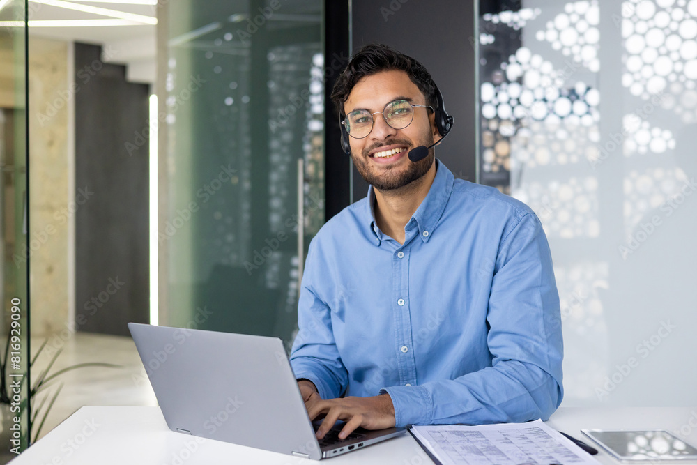 Smiling customer service representative using laptop in modern office environment Smiling customer service representative using laptop in modern office environment
