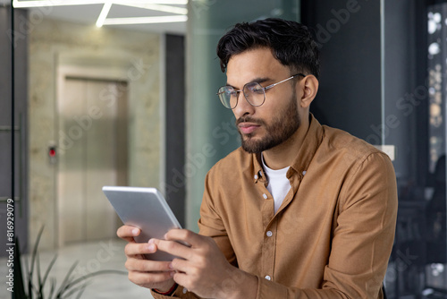 Focused man using a tablet in a modern office environment photo