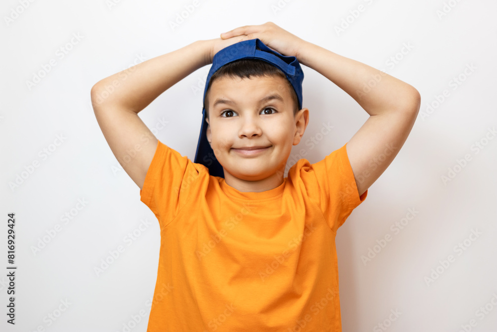 A cheerful boy in an orange T-shirt grabbed his head. Sincere children's emotions. A cheerful boy in an orange T-shirt grabbed his head. Sincere children's emotions.