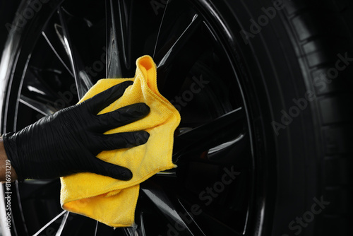car detailing. hand is cleaning a black alloy wheel with microfiber cloth