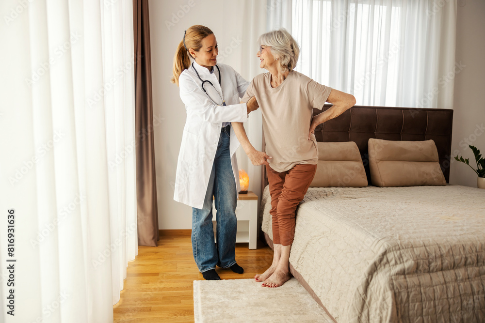 Doctor is helping senior woman to walk in bedroom during her home visit. Doctor is helping senior woman to walk in bedroom during her home visit.