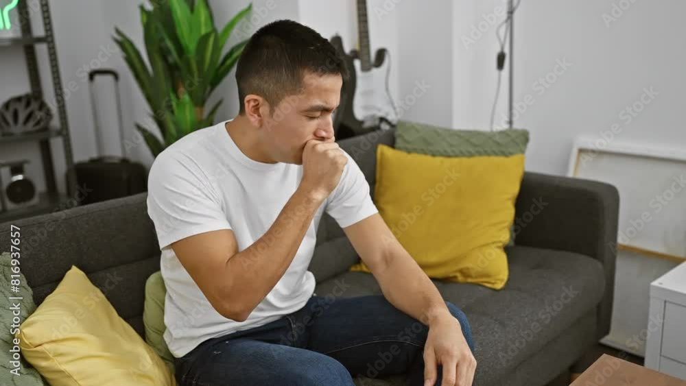 A thoughtful young hispanic man sitting in a modern living room, looking pensive and reflective. A thoughtful young hispanic man sitting in a modern living room, looking pensive and reflective.