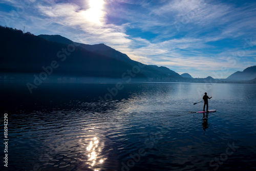 Man on a Paddleboard on Lake Lugano with Sunlight and Mountain in Ticino, Switzerland.