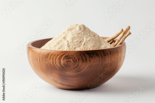 Wooden bowl filled with fine ashwagandha powder and raw roots against a clean, white background, embodying health and ayurveda