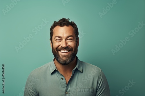 Portrait of a happy man in his 40s smiling at the camera in soft teal background